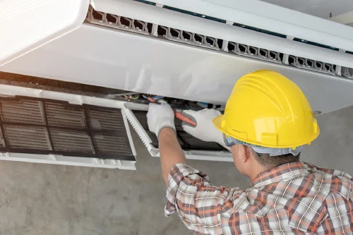 A technician performing regular AC maintenance on a home condenser unit.