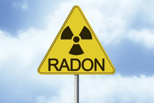 A home with a warning sign that reads, “The Hidden Dangers of Radon Gas in Indoor Air”.
